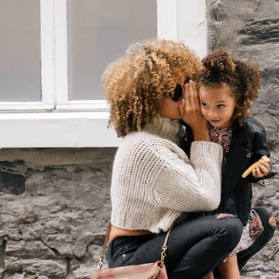 babysitter whispering into child's ear