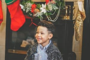 smiling boy by Christmas mantle