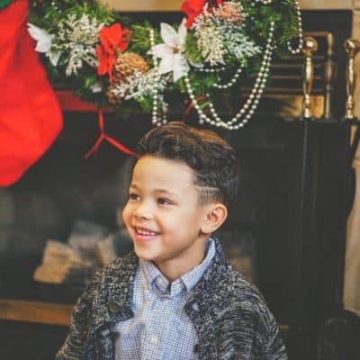 smiling boy by Christmas mantle