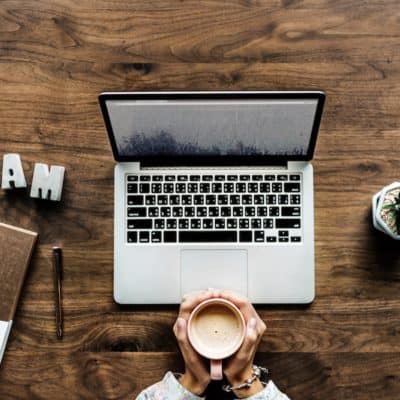 woman with laptop holding coffee