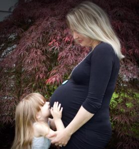 little girl kissing pregnant moms belly