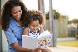 Girl and mom reading book and laughing