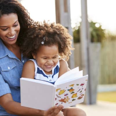 Girl and mom reading book and laughing