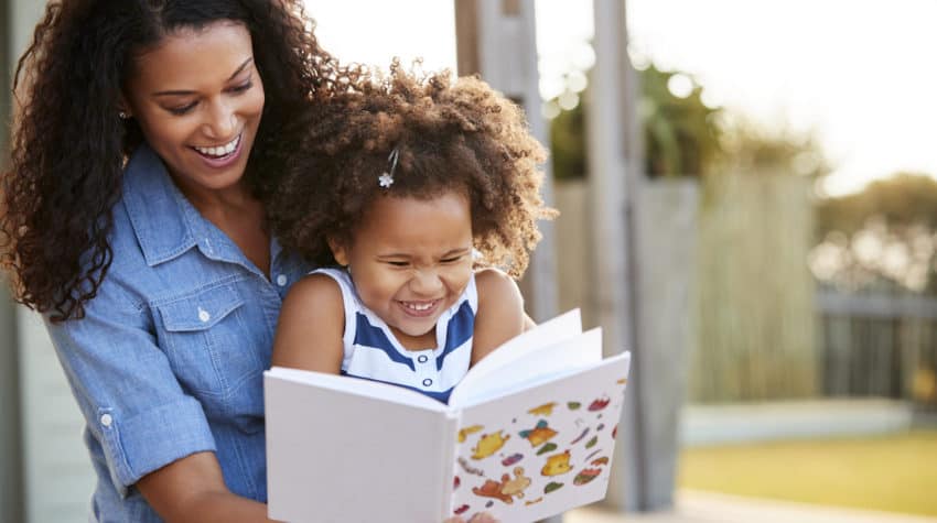 Girl and mom reading book and laughing