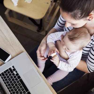 busy mom working with baby on lap