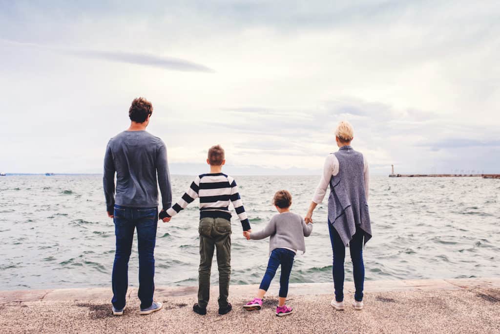 family staring at the ocean and holding hands