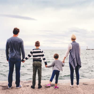 family staring at the ocean and holding hands