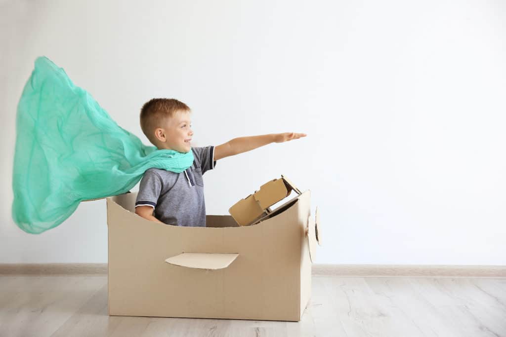 boy pretending to be superhero in a cardboard airplane