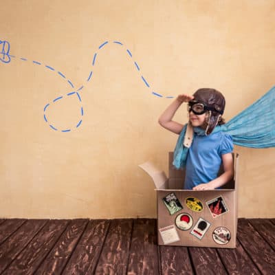 young girl sitting in a box imagining she's in a plane