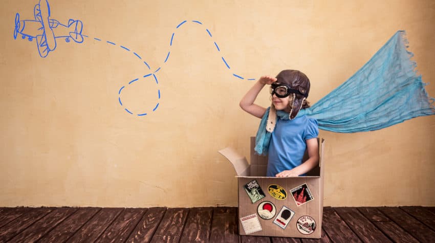 young girl sitting in a box imagining she's in a plane