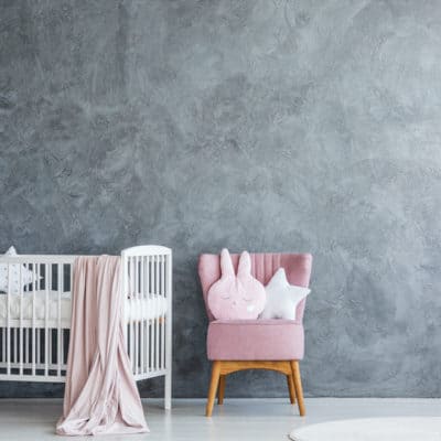 empty white crib against gray wall in baby nursery