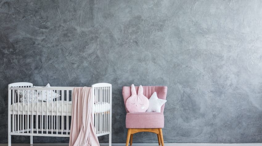 empty white crib against gray wall in baby nursery