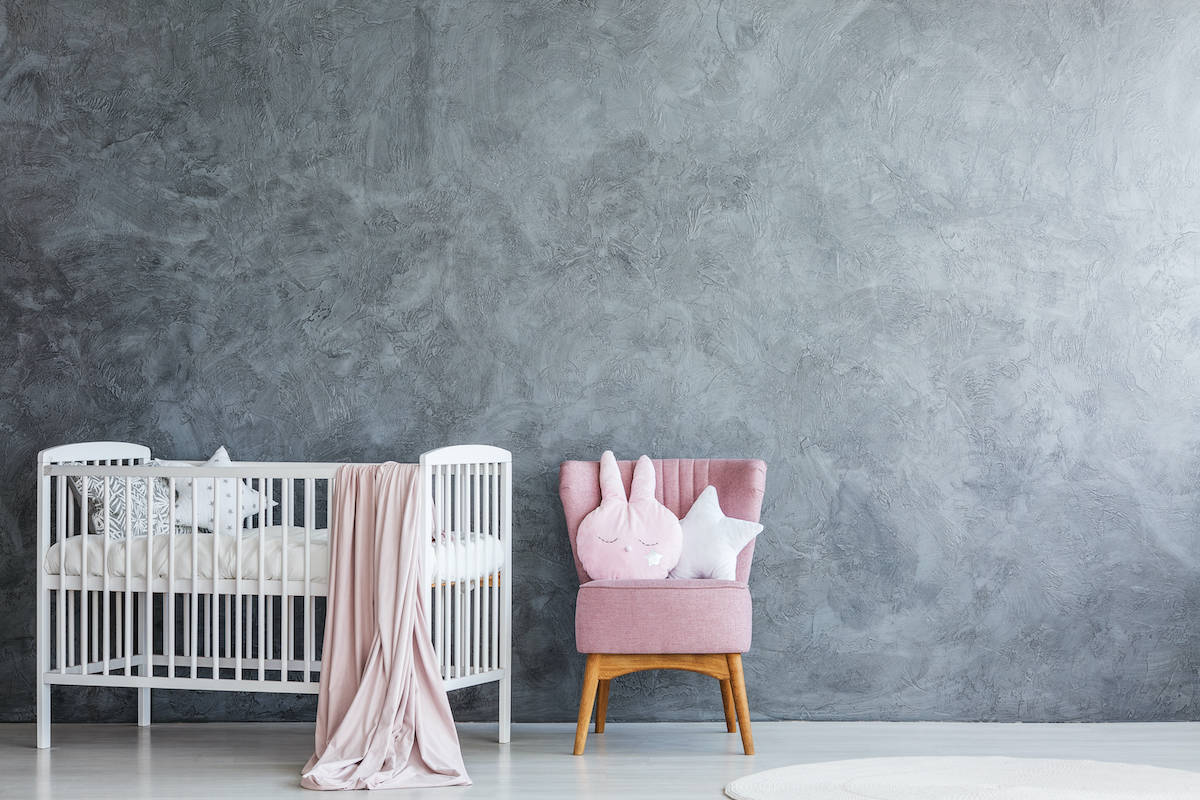 empty white crib against gray wall in baby nursery