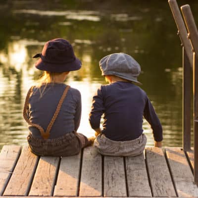 2 kids sitting on a dock in summer