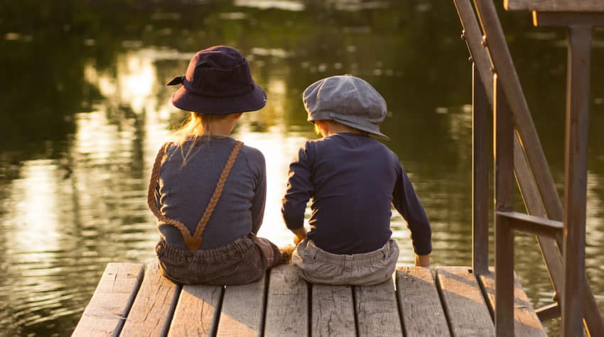 2 kids sitting on a dock in summer