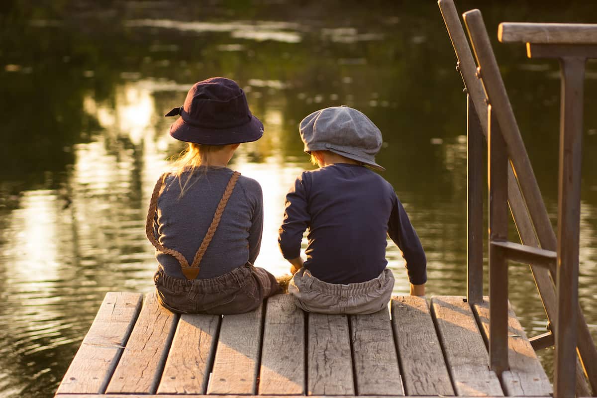 two kids sitting on a dock fishing