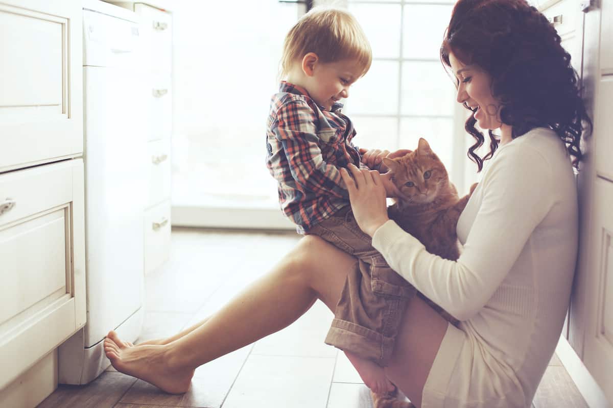 mother holding smiling toddler and cat