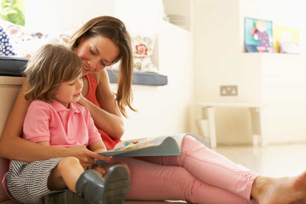 Mother Sitting With Son Reading Story Indoors.