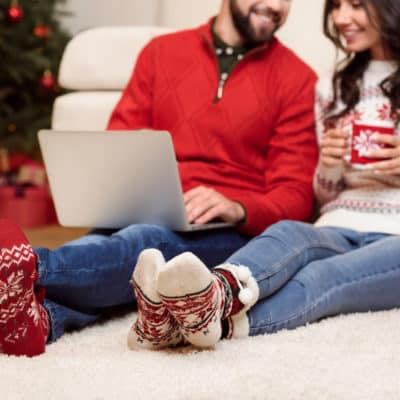 couple smiling at each other holding Christmas mug and laptop