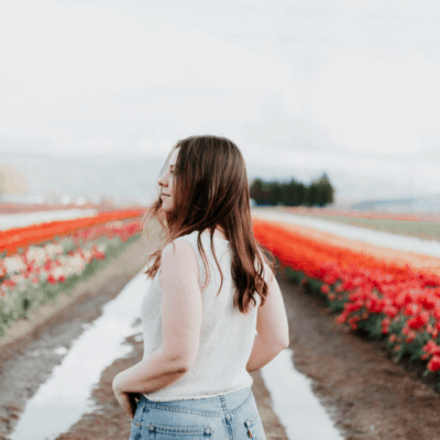 young woman staring into a field of red and white flowers