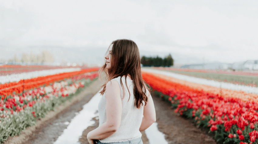 young woman staring into a field of red and white flowers