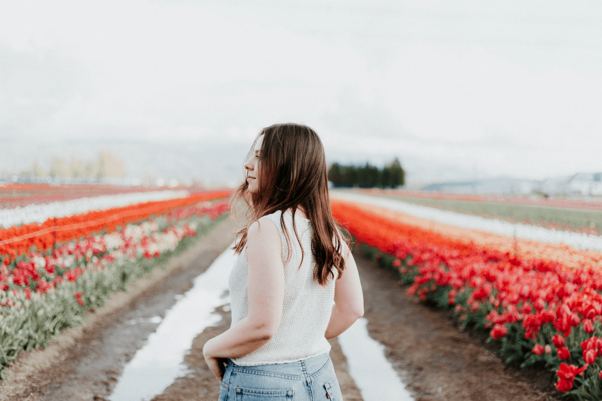 young woman staring into a field of red and white flowers