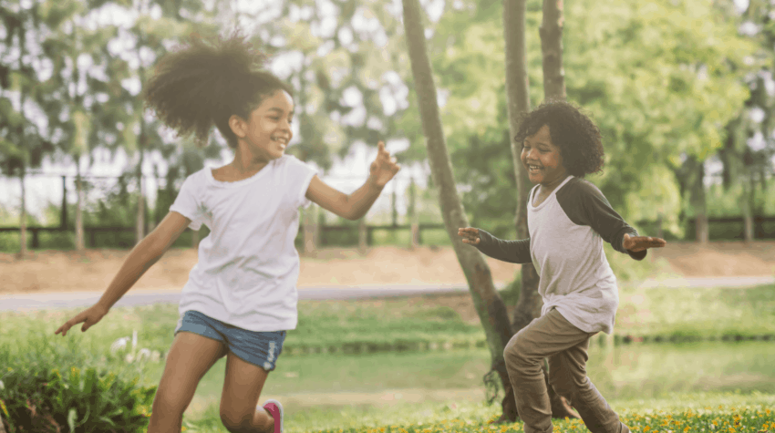 two kids running and playing in the grass