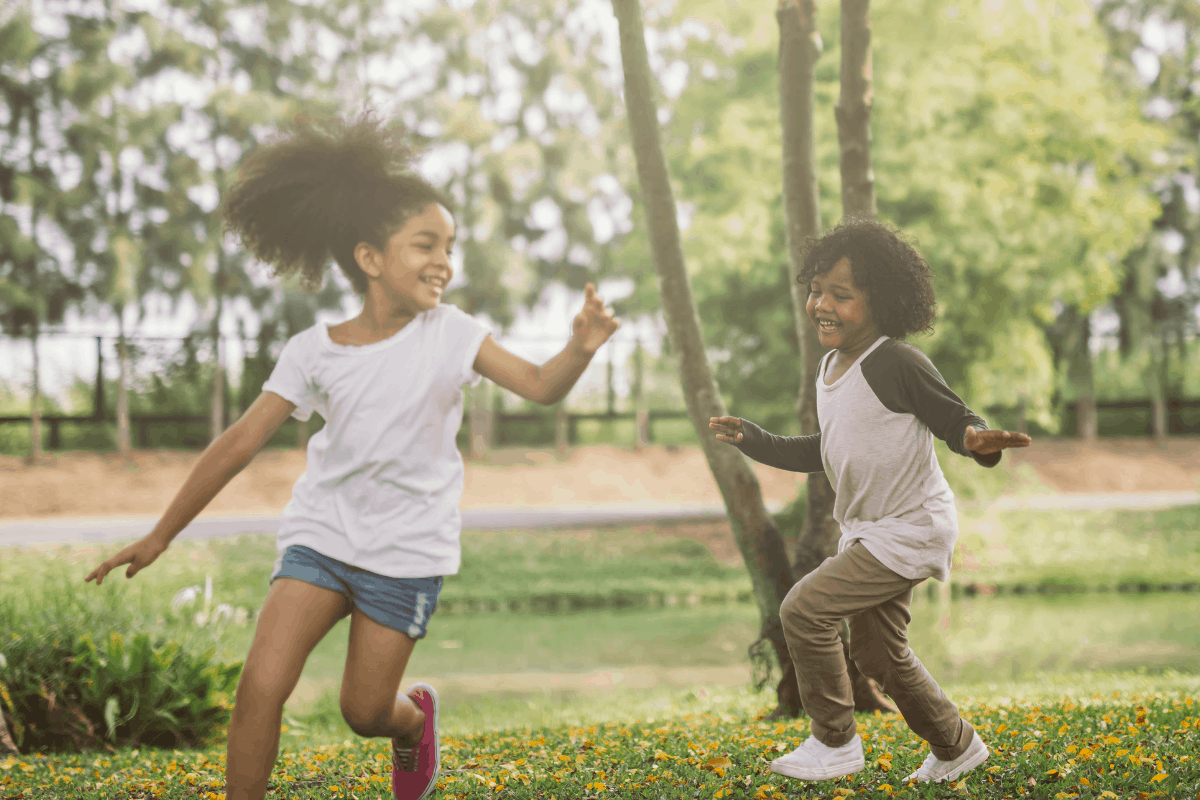 two kids running and smiling in the green grass